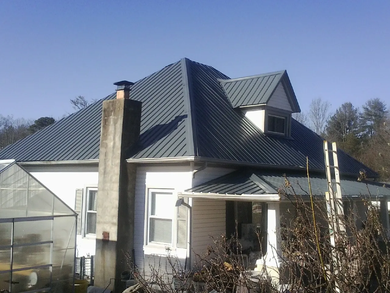 Dark blue standing seam metal roof on a white farmhouse with dormer — Slate & Tile Roof Repair by Roofing Brothers in Aiken