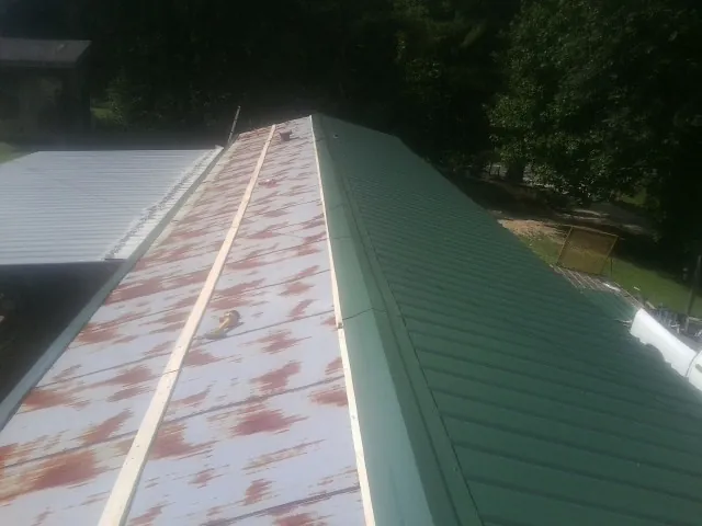 Old rusted panels beside newly installed green metal roofing — Wind Damage Roof Repair by Roofing Brothers in Aiken