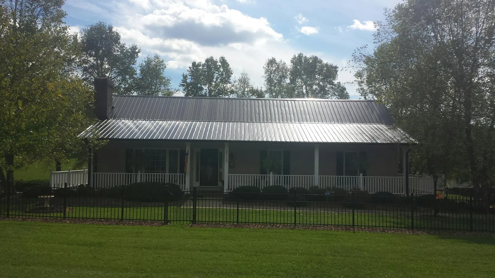 Gray metal roof on a brick ranch with a full width front porch — Gutter Guard Installation work by our crew in Aiken