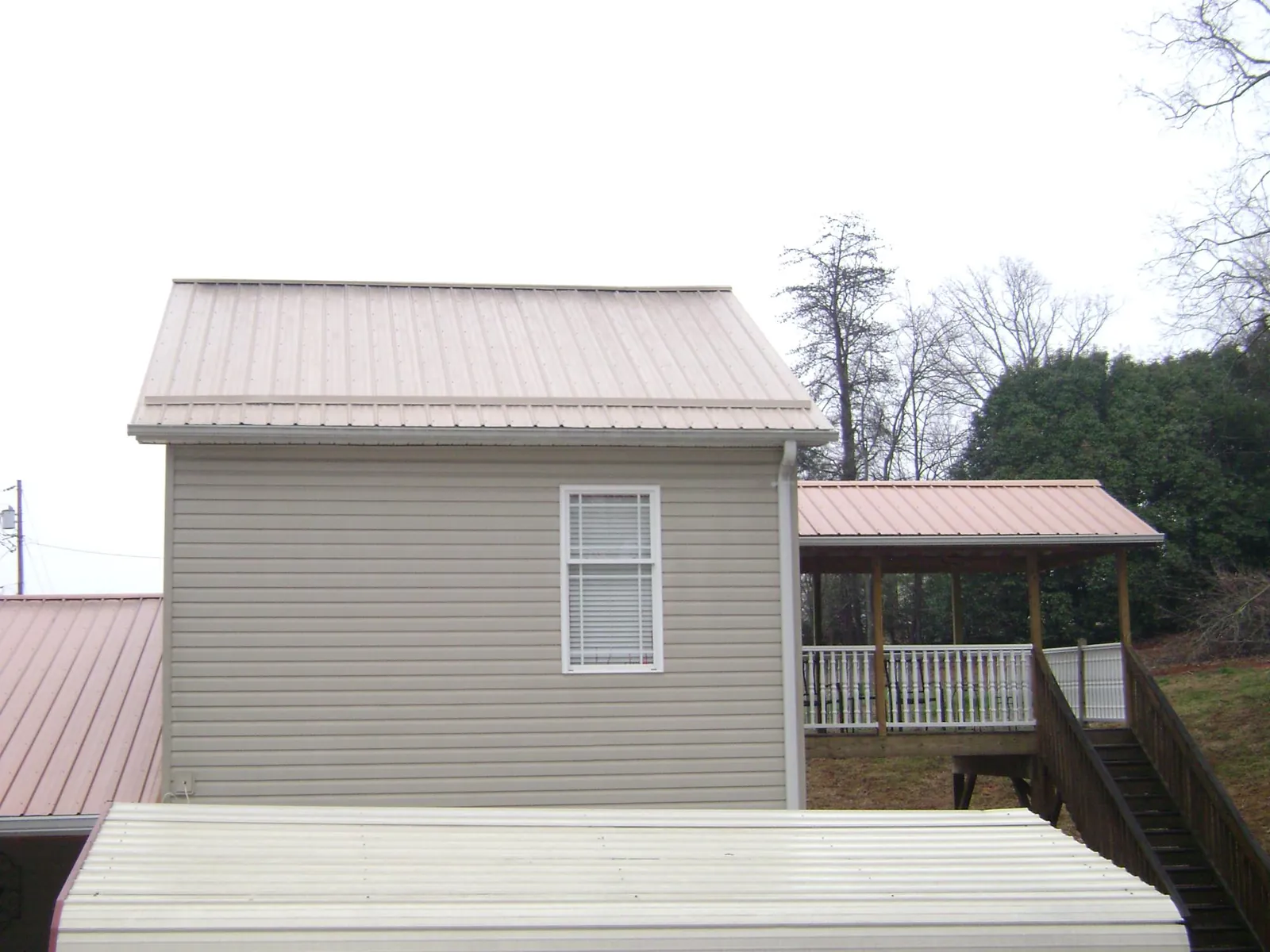 Tan metal roofs on a two story addition and attached porch, from a Roof Replacement job in Aiken