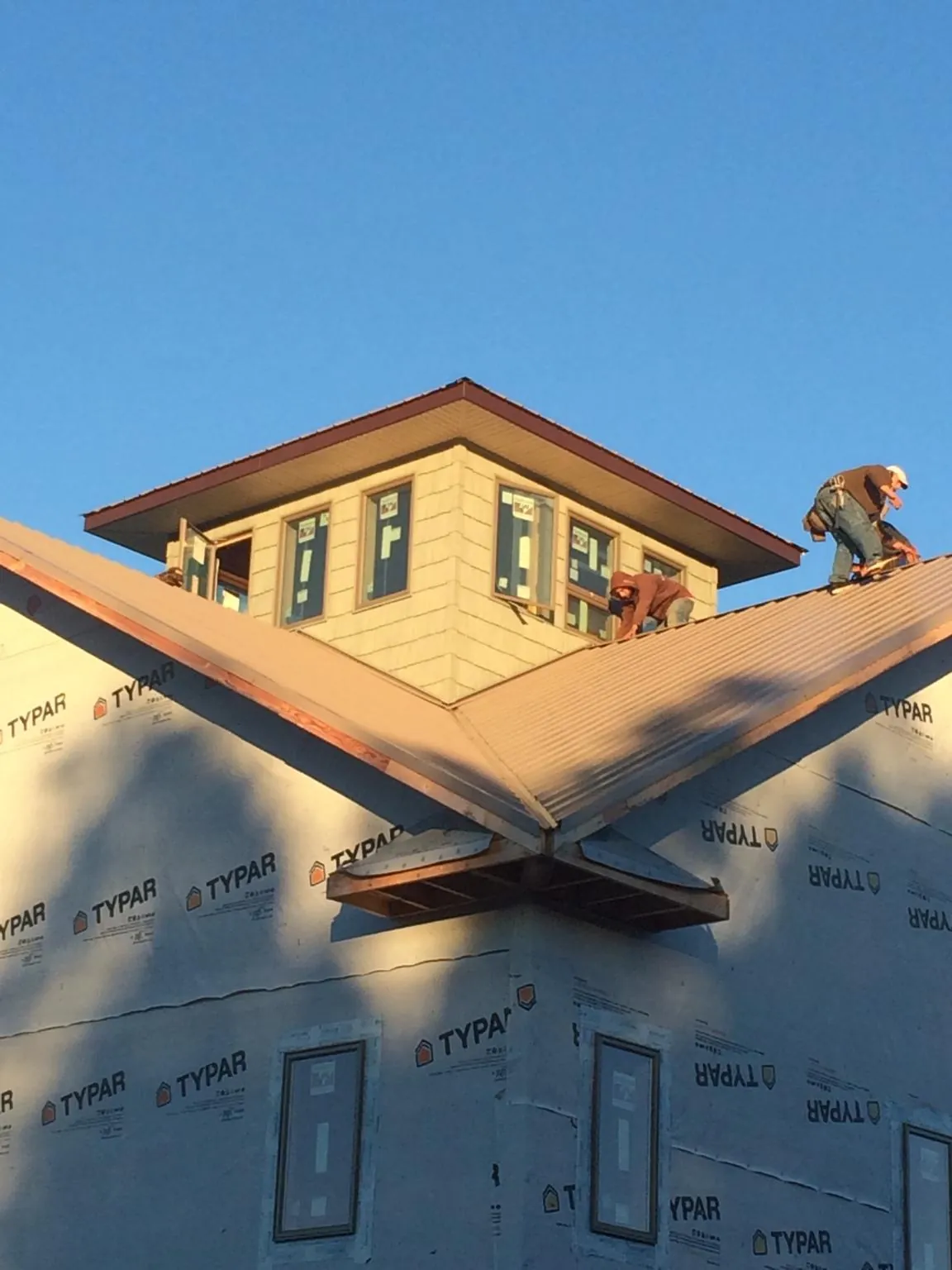 Roofers working around a rooftop cupola on a new metal roof at sunset — Roof Waterproofing in Aiken by Roofing Brothers